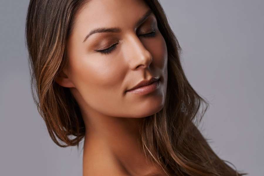 Un portrait en gros plan d'une femme avec un maquillage subtil et un teint glowy ultra-lumineux.
